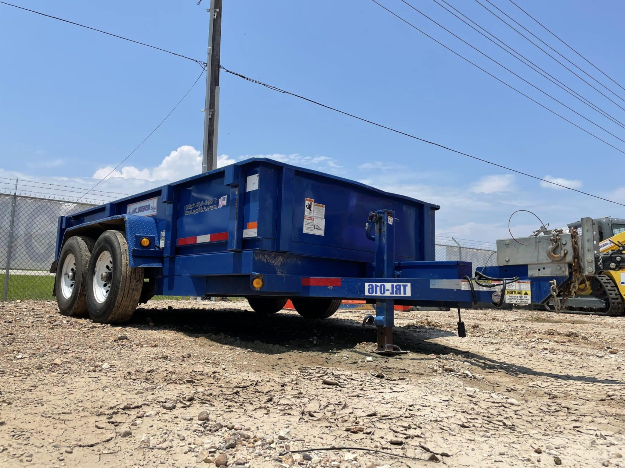Blue dump trailer parked on gravel
