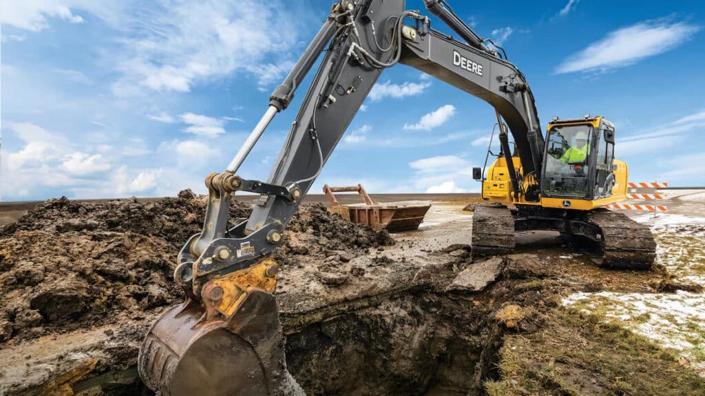 A John Deere excavator moving dirt on a construction field.