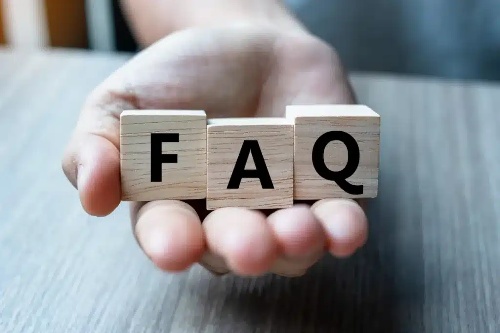 Hand holding wooden blocks that read FAQ
