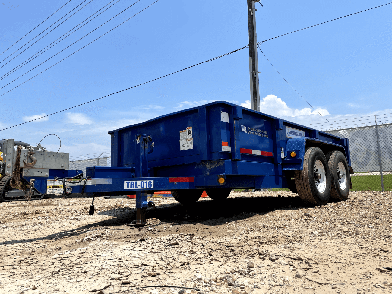 Blue dump trailer parked outside.