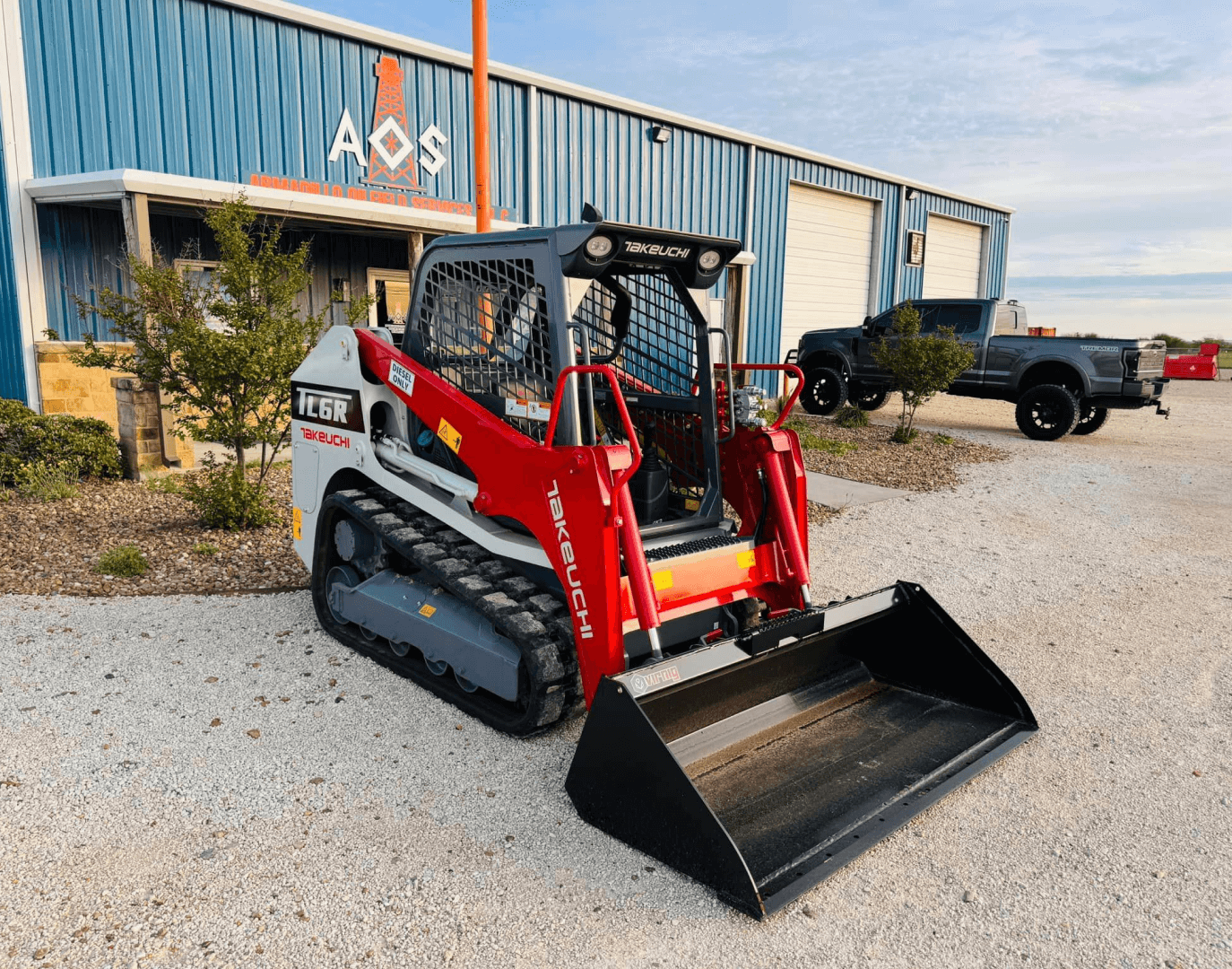 Takeuchi TL6R," "compact track loader," "construction equipment," "AOS building," "red and white loader," "construction site.