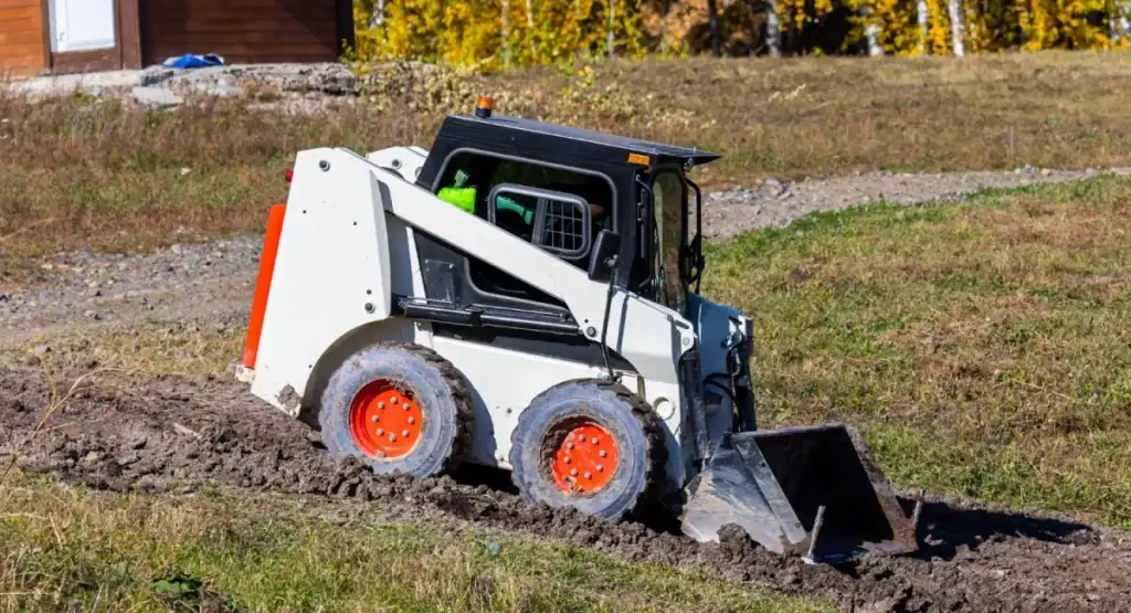 Compact White Skid Steer with Orange Wheels in Residential Setting